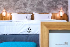 a bedroom with two beds with white sheets and lights at Senso Suites in Nea Peramos
