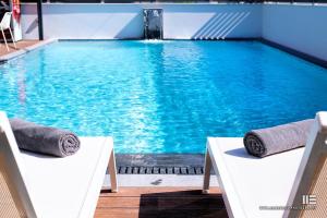 a large swimming pool with two chairs in front of it at Senso Suites in Nea Peramos