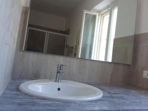 een witte wastafel in een badkamer met een spiegel bij trulli l'utopia di Anny trulli Anny's utopia in Locorotondo