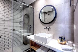 a bathroom with a sink and a mirror and a shower at Senso Suites in Nea Peramos