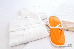 a white shirt and an orange shoe on a bed at Senso Suites in Nea Peramos