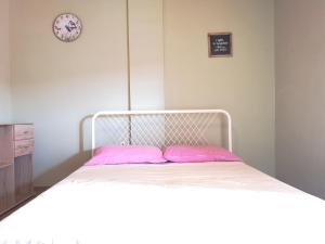 a white bed with pink pillows in a bedroom at Apartments Sandra in Lopar