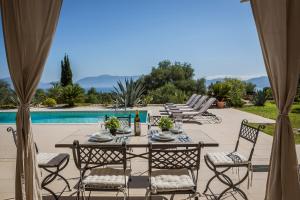 a patio with a table and chairs next to a pool at Villa Agapi Mou in Karavomylos