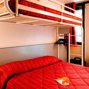 Schlafzimmer mit einem Bett mit einer roten Bettdecke in der Unterkunft Premiere Classe Saint Nazaire - Trignac in Trignac