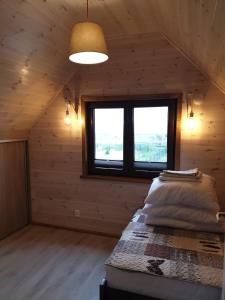 ein Schlafzimmer in einem Blockhaus mit einem Bett und einem Fenster in der Unterkunft Los Reyes II - klimatyzowane domki in Krynica Morska