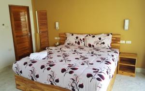 a bedroom with a large bed with a floral bedspread at Oasis Apartments & Bar in Karon Beach