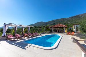 a swimming pool in a yard with chairs and a house at Villa Oliva in Kaštela