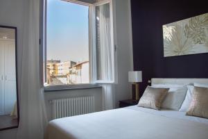 una camera con un letto bianco e una grande finestra di AMA Casa a Pisa