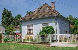 a small blue house with a white fence at Anna Vendégház in Harkány
