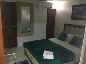 a bedroom with a bed with a green blanket and mirrors at Hotel Atardecer Guajiro in Ríohacha +2 photos