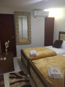 a hotel room with two beds and a mirror at Hotel Atardecer Guajiro in Ríohacha