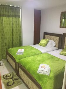 two beds in a room with green sheets and towels at Hotel Atardecer Guajiro in Ríohacha