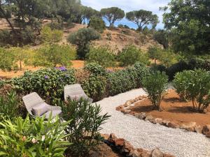 2 chaises dans un jardin planté de fleurs et d'arbres dans l'établissement Casa Sereno, à Benagil