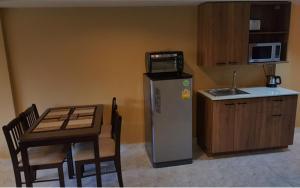 eine Küche mit einem Tisch, einem Kühlschrank und einer Mikrowelle in der Unterkunft Oasis Apartments & Bar in Karon Beach