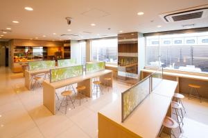 una cafetería con mesas y taburetes en un edificio en Super Hotel Tokyo JR Shinkoiwa en Tokio