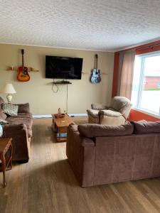 uma sala de estar com 2 sofás e uma televisão de ecrã plano em Exploits Inn and Suites em Botwood