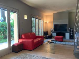 a living room with a red couch and a television at Exclusive Loft by the sea 400mt in Forte dei Marmi