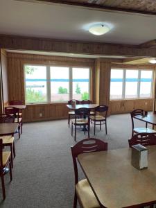 ein Esszimmer mit Tischen, Stühlen und Fenstern in der Unterkunft Exploits Inn and Suites in Botwood
