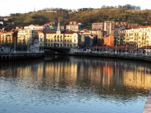 a city with a river with buildings and a bridge at Casa Narolai in Bilbao