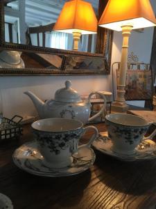 a wooden table with two tea cups and a lamp at B&B les Agapanthes in Gasny