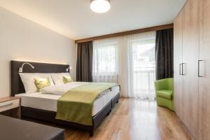 una camera con letto e sedia verde di Ciasa MAEL Dolomites Apartments a La Valle