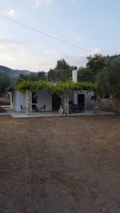 a white building with a table and chairs in a field at Villa Glaykos in Thymonia Beach