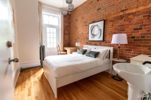 a bedroom with a white bed and a brick wall at Auberge du Plateau in Montreal