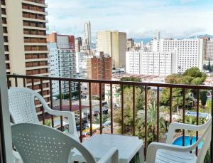 einen Balkon mit einem Tisch und Stühlen sowie eine Stadt in der Unterkunft Apartamento Benidorm Luxury Levante in Benidorm