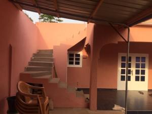 a pink building with a staircase in front of a house at MINI VILLA ROSE in Lomé
