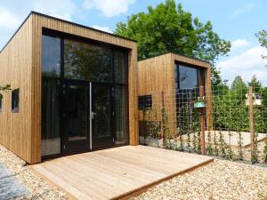 ein kleines Haus mit Glastüren und einer Holzterrasse in der Unterkunft Trendy Tiny Houses Bovenweg in Rhenen