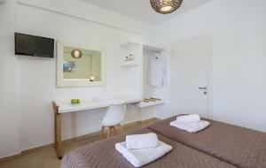 a white room with two beds and a desk at The Wave in Sidari