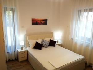 a bedroom with a bed with two lamps and two windows at Casa Maria Mamaia Nord in Mamaia Sat/Năvodari