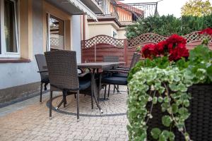 een patio met stoelen en een tafel met rode bloemen bij Apartamenty Tercet, Apartament Kwartet, Apartament DUO in Ustka