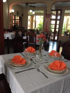 einen Tisch mit Tellern und Küchenutensilien auf einem weißen Tischtuch in der Unterkunft Hotel El Reformador in Puerto Barrios
