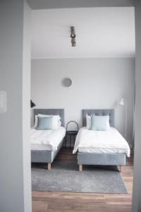 twee bedden in een slaapkamer met witte muren en houten vloeren bij TS Budget Stay in Szczecin