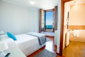1 dormitorio con cama y vistas al océano en Apartamentos Villa Zoila Baiona, en Baiona