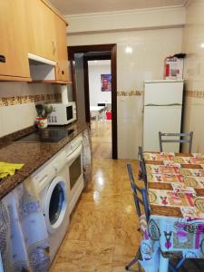 a kitchen with a washing machine and a table at Alojamiento Quintanilla in Gijón