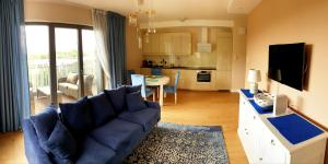 a living room with a blue couch and a kitchen at Apartament North Coast - nad morzem in Gdańsk