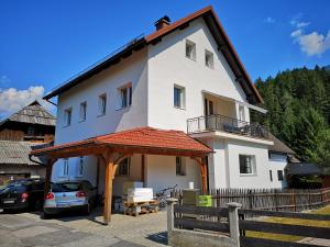 Una casa blanca con un coche aparcado delante. en Apartma EVA&MATIC, en Kranjska Gora