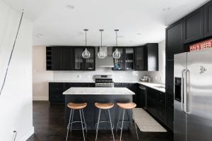 uma cozinha com armários pretos e uma ilha de cozinha com bancos em Charming Rustic Modern House Near Royal Oak em Pleasant Ridge