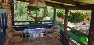 un porche con mesa, sillas y flores en Pensiunea Anita, en Vişeu de Sus