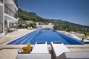 a villa with a swimming pool with mountains in the background at Highclere Hotel and Spa in Faralya