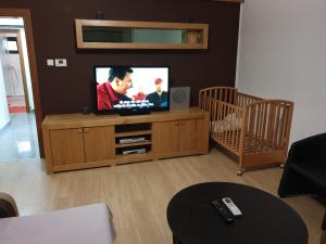 a living room with a flat screen tv and a crib at Apartman Max 2 in Biškupec Zelinski