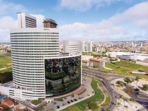 a large white building in a city with traffic at Flat novo no Complexo Heron Marinho in Campina Grande