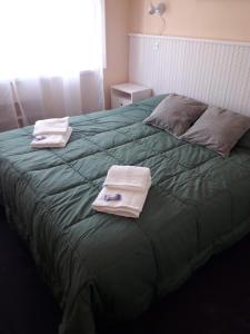 1 dormitorio con 2 toallas en una cama verde en Danny ap - Amplio y cómodo - 18 min Aeropuerto - Zona de Restos - Parking en Monte Grande