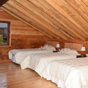 two beds in a room with wooden ceilings at Lodge El Sarao A Una Hora De Puerto Varas in Fresia