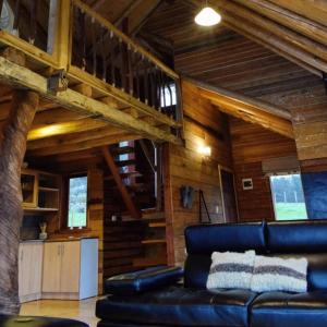 un soggiorno con divano in pelle in una cabina di Lodge El Sarao A Una Hora De Puerto Varas a Fresia