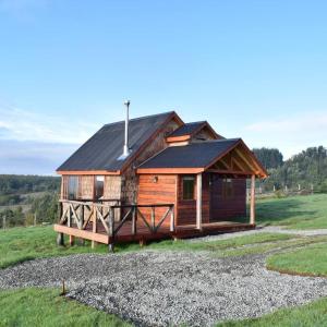 a large wooden cabin in a grassy field at Lodge El Sarao A Una Hora De Puerto Varas in Fresia