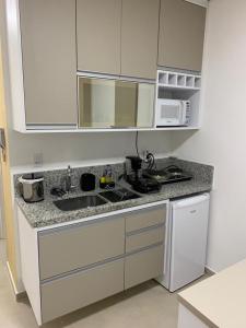 a kitchen with a sink and a microwave at Flat Granja Viana in Cotia