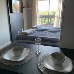 a table with two bowls and a wine glass in a bedroom at Flat Granja Viana in Cotia
